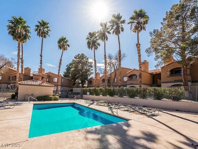 community pool with a patio, a residential view, and fence