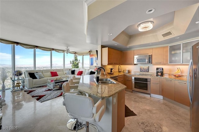 kitchen featuring a sink, a peninsula, stainless steel appliances, a breakfast bar area, and open floor plan