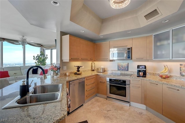 kitchen featuring light stone countertops, stainless steel appliances, visible vents, and a sink