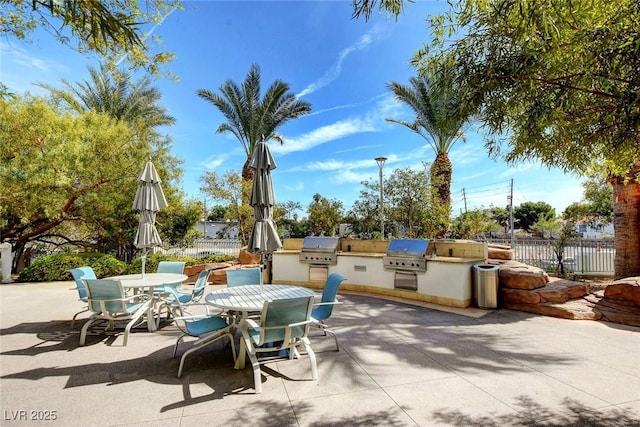 view of patio featuring exterior kitchen, outdoor dining area, fence, and area for grilling