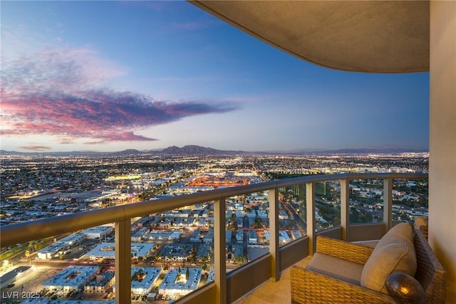 balcony at dusk featuring a city view and a mountain view