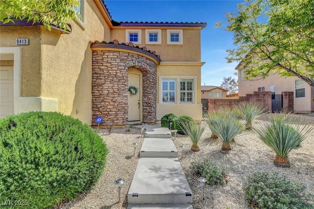 9413 Artesian Oak Ct, Las Vegas, NV 89149 - doorway to property featuring fence, a tile roof, stone siding, and stucco siding