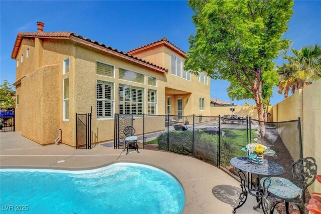 9413 Artesian Oak Ct, Las Vegas, NV 89149 - rear view of property featuring a tile roof, a patio area, fence, a fenced in pool, and stucco siding