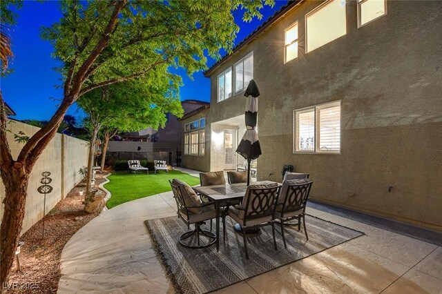 9413 Artesian Oak Ct, Las Vegas, NV 89149 - patio at twilight featuring a yard, outdoor dining area, and a fenced backyard