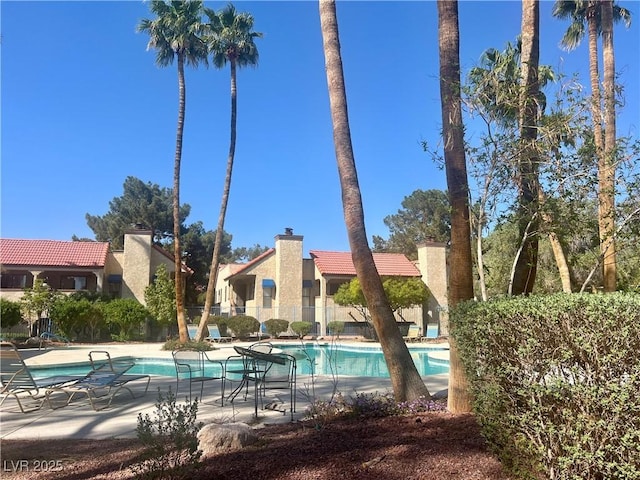 community pool with a patio area and fence
