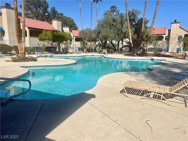 pool with a patio area and fence