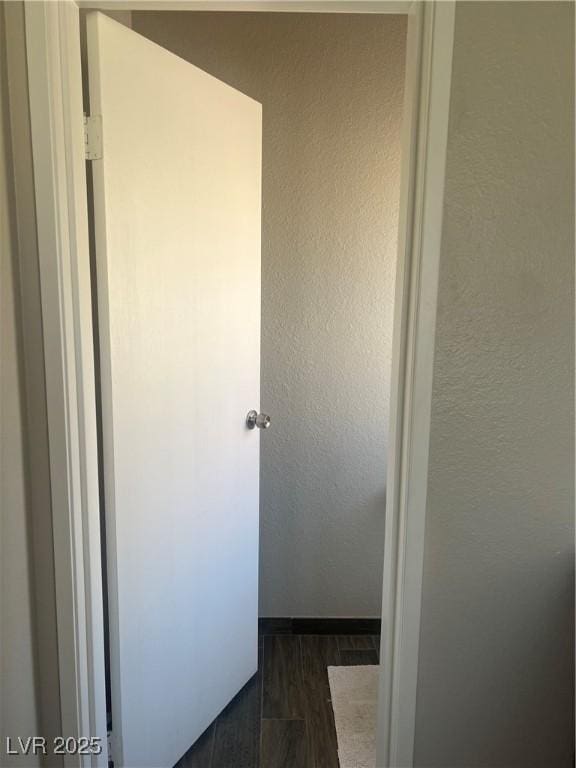 corridor featuring a textured wall and dark wood-style flooring