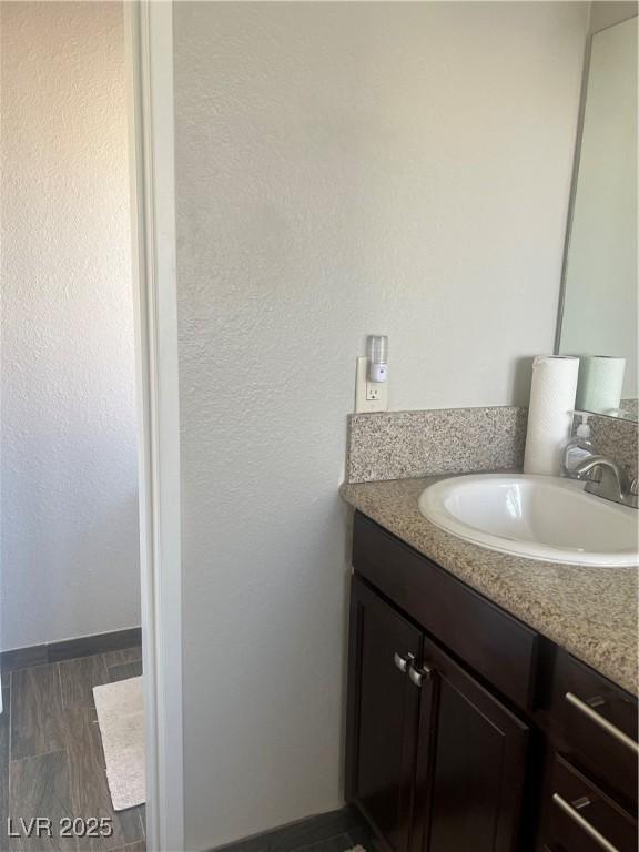 bathroom with wood finished floors, vanity, and baseboards