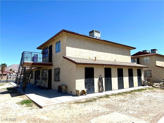 rear view of house featuring central air condition unit, a patio, stairway, and stucco siding