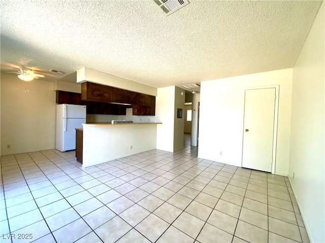unfurnished living room featuring light tile patterned flooring, a textured ceiling, ceiling fan, and visible vents