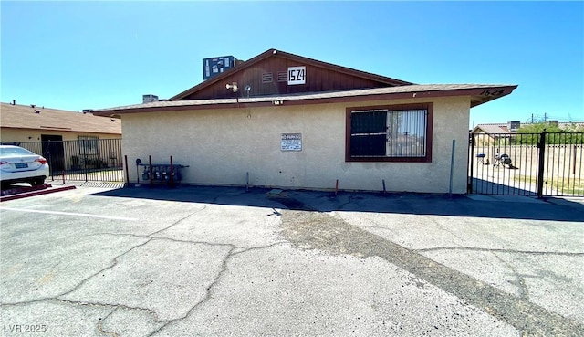view of property exterior featuring fence, uncovered parking, and stucco siding