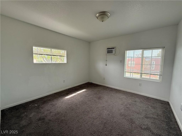 unfurnished room featuring dark carpet, a textured ceiling, a wall unit AC, and baseboards