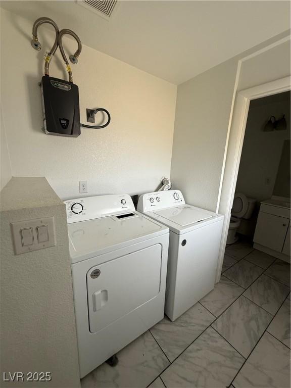 clothes washing area with washer and dryer, laundry area, marble finish floor, and visible vents