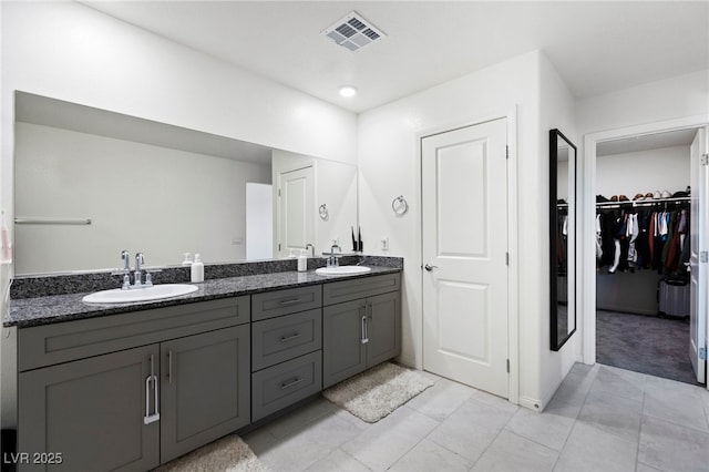 full bathroom featuring double vanity, a walk in closet, and tile patterned flooring