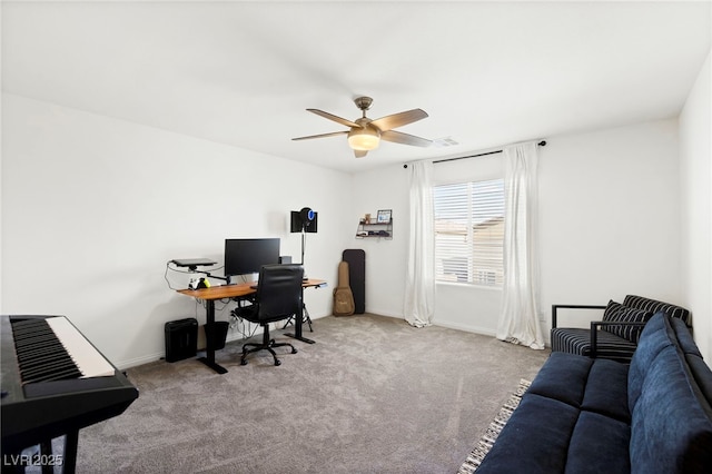 carpeted office space with a ceiling fan and baseboards