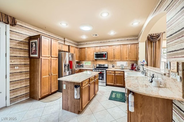 215 Sunset Shower Dr, Henderson, NV 89012 - kitchen with light stone counters, appliances with stainless steel finishes, brown cabinets, a sink, and a center island