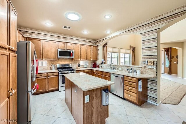 215 Sunset Shower Dr, Henderson, NV 89012 - kitchen with arched walkways, stainless steel appliances, a center island, a sink, and visible vents