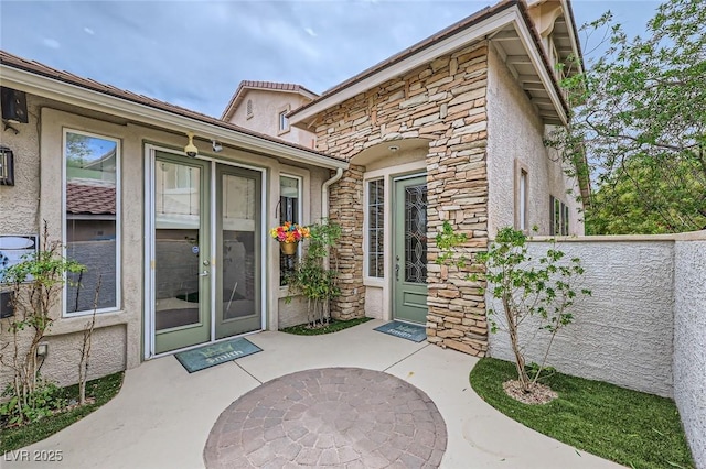 215 Sunset Shower Dr, Henderson, NV 89012 - property entrance with fence, a patio area, stucco siding, and stone siding