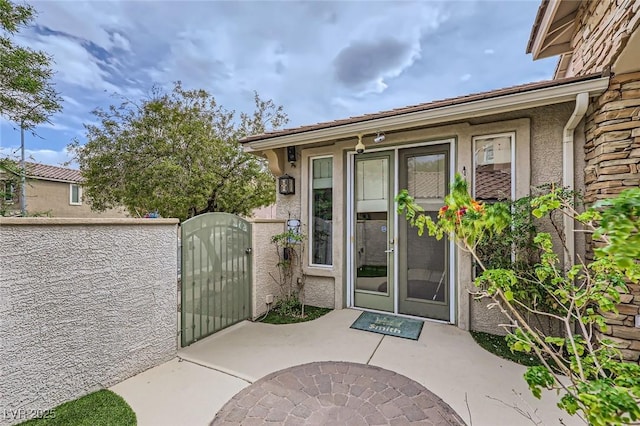 215 Sunset Shower Dr, Henderson, NV 89012 - view of exterior entry with a gate, fence, and stucco siding
