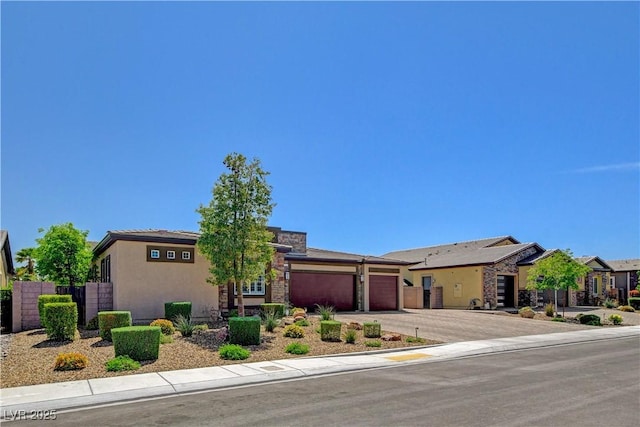view of front of home featuring stucco siding, fence, stone siding, an attached garage, and concrete driveway
