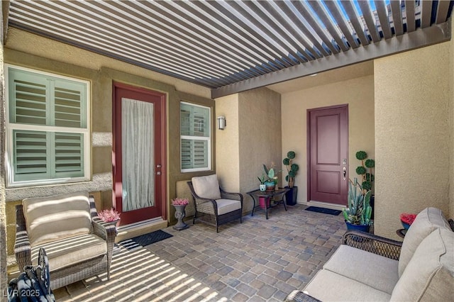 view of exterior entry with a pergola and stucco siding