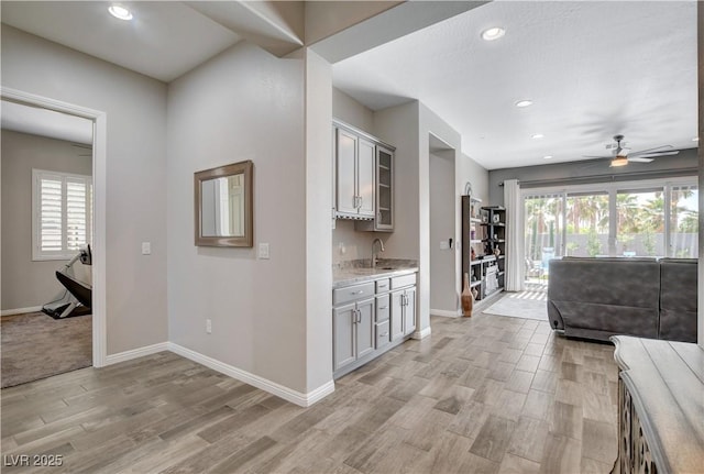 interior space featuring a wealth of natural light, baseboards, light wood-type flooring, and a sink