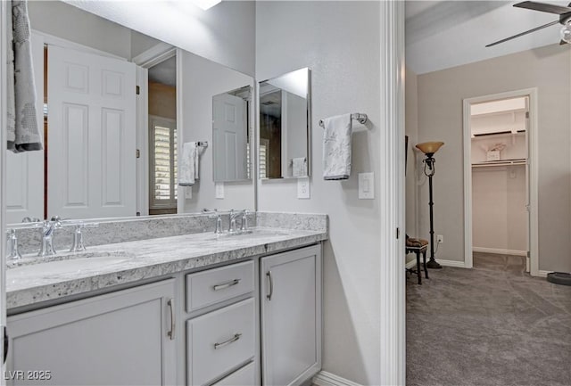 full bathroom with double vanity, a sink, a ceiling fan, and baseboards