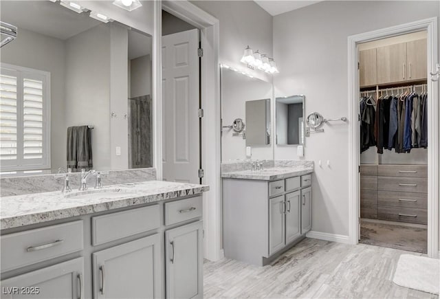 bathroom with two vanities, a sink, and a walk in closet