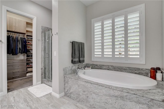 full bath with a shower stall, a walk in closet, and a bath