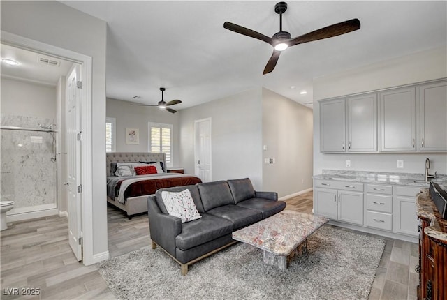 bedroom with visible vents, baseboards, a sink, light wood-style floors, and connected bathroom