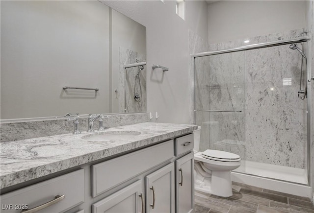 bathroom featuring toilet, a stall shower, wood finished floors, and vanity