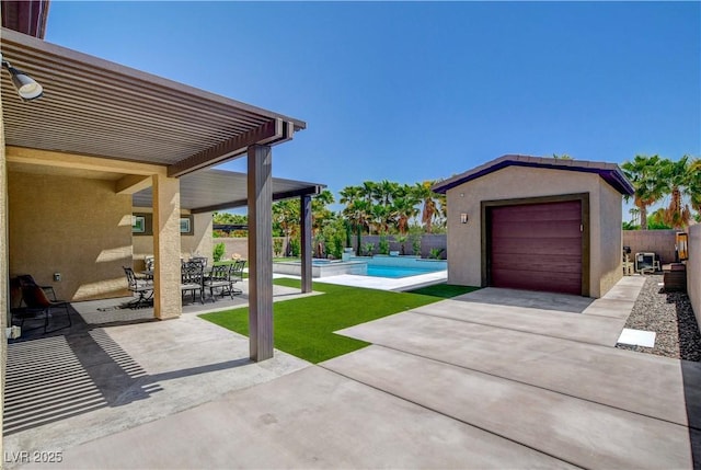 exterior space featuring concrete driveway, a detached garage, an outbuilding, a pool with connected hot tub, and fence
