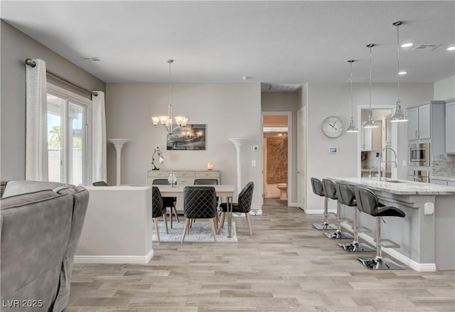 dining area with a notable chandelier, baseboards, recessed lighting, light wood-style flooring, and visible vents