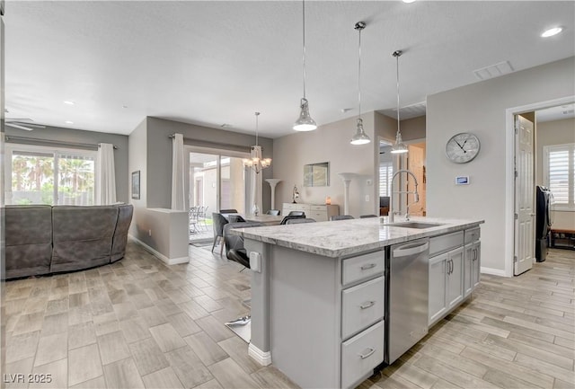 kitchen with baseboards, open floor plan, visible vents, stainless steel dishwasher, and a sink