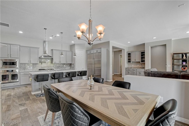 dining area featuring light wood finished floors, a notable chandelier, visible vents, and recessed lighting