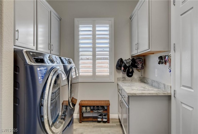 laundry area featuring cabinet space, light wood-style flooring, washer and dryer, and baseboards