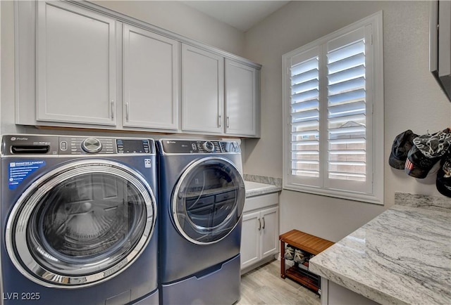 laundry area featuring separate washer and dryer, light wood-style flooring, and cabinet space