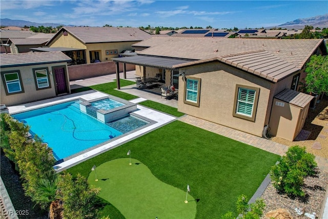 view of swimming pool with a pool with connected hot tub, a lawn, a patio area, a mountain view, and a residential view
