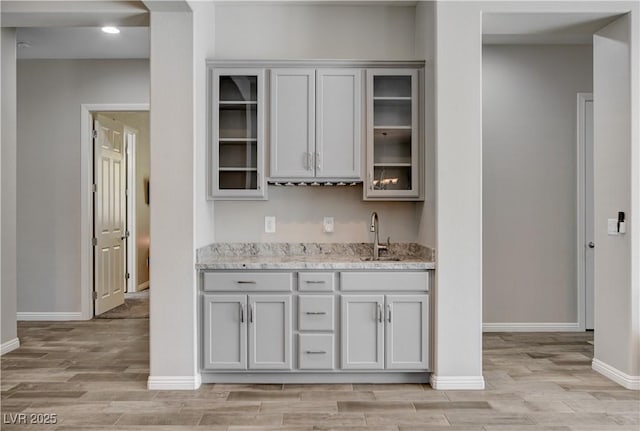 kitchen with gray cabinetry, light wood finished floors, and a sink