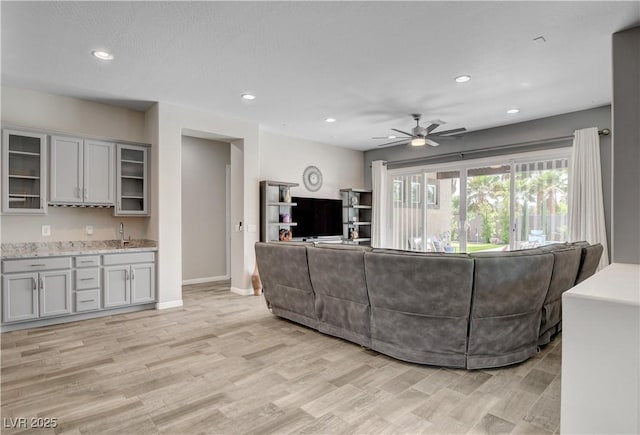 living room with light wood-style flooring, a ceiling fan, recessed lighting, and baseboards