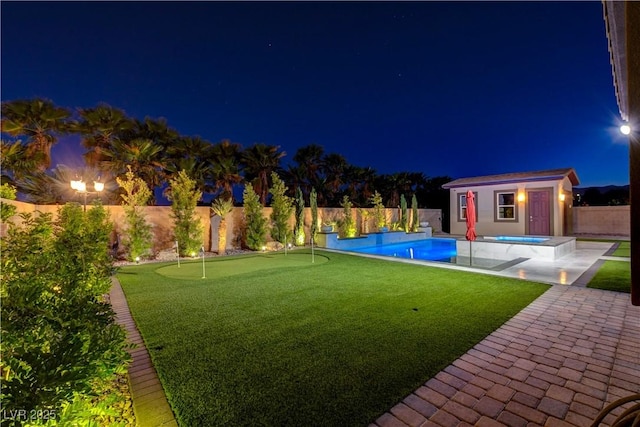 yard at night featuring a fenced in pool, an exterior structure, a patio area, a fenced backyard, and an outbuilding