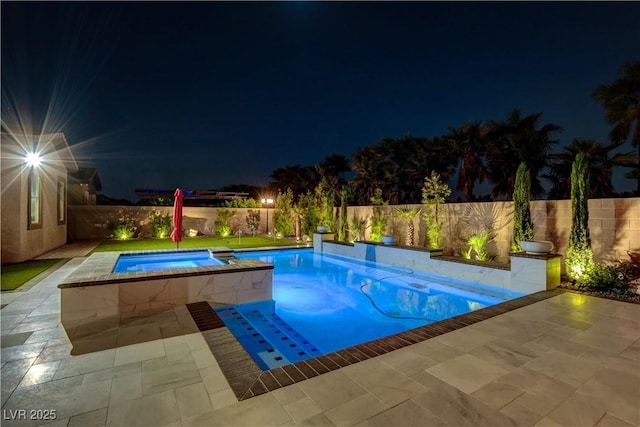 pool at night with a patio, a fenced backyard, and an in ground hot tub