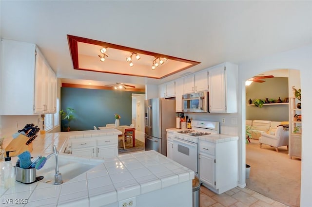 4517 Inez Dr, Las Vegas, NV 89130 - kitchen featuring appliances with stainless steel finishes, a ceiling fan, tile countertops, white cabinets, and a peninsula