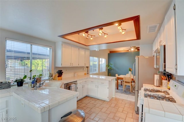 4517 Inez Dr, Las Vegas, NV 89130 - kitchen featuring a tray ceiling, tile countertops, a peninsula, and white gas range oven