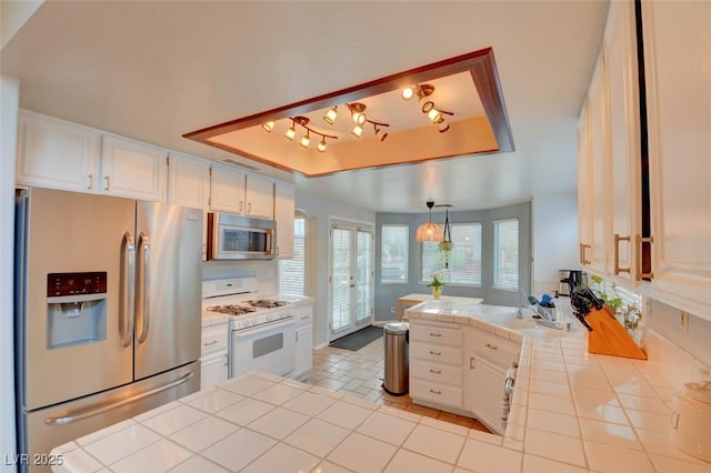 4517 Inez Dr, Las Vegas, NV 89130 - kitchen with appliances with stainless steel finishes, a raised ceiling, tile counters, white cabinets, and a peninsula