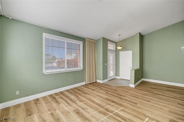 spare room featuring baseboards, vaulted ceiling, and wood finished floors