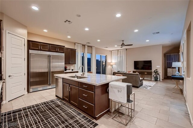 kitchen with visible vents, dark brown cabinetry, stainless steel appliances, and a sink