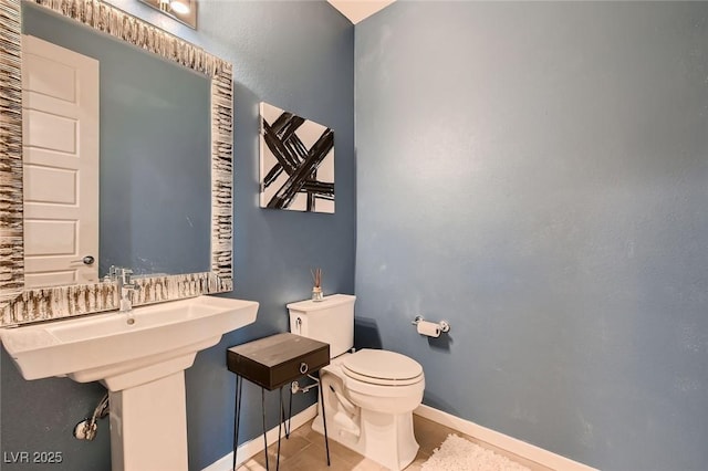 half bath with toilet, tile patterned flooring, and baseboards