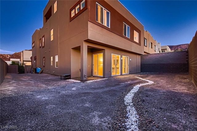 rear view of house featuring a fenced backyard and stucco siding