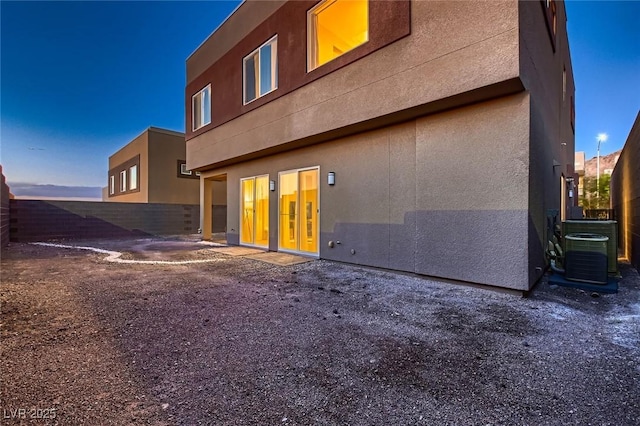 rear view of house featuring fence, central AC, and stucco siding